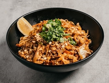 pad thai chicken, רוטב חמוץ מתוק, אטריות אורז, ביצה, רצועות עוף, כרוב גזר, נבטים, בצל ירוק, כוסברה, בוטנים קצוצים ופלח לימון.