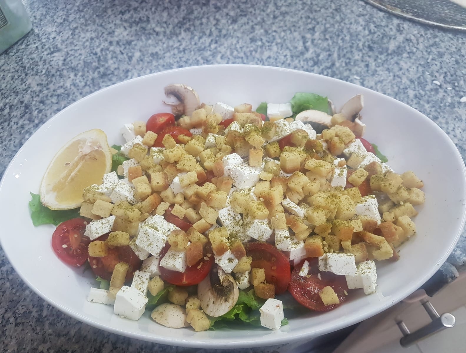 סלט קיסר, חסה, עלי בייבי, קרוטונים, קוביות בולגרית, עגבניות שרי ופטריות ברוטב ויניגרט.