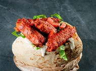 Seekh Kebab, ground lamb meat kebab, seasoned with spices, roasted in the tandoor, tahini, fresh greens, red onion, tomato and pickles.